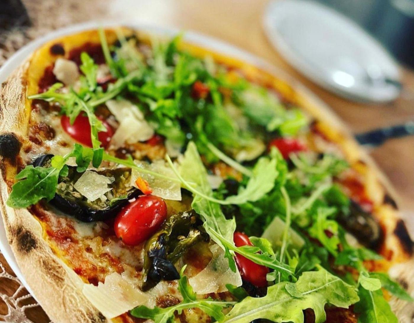 Pizza mit Rucola, gegrilltem Gemüse und Oliven im La Riva