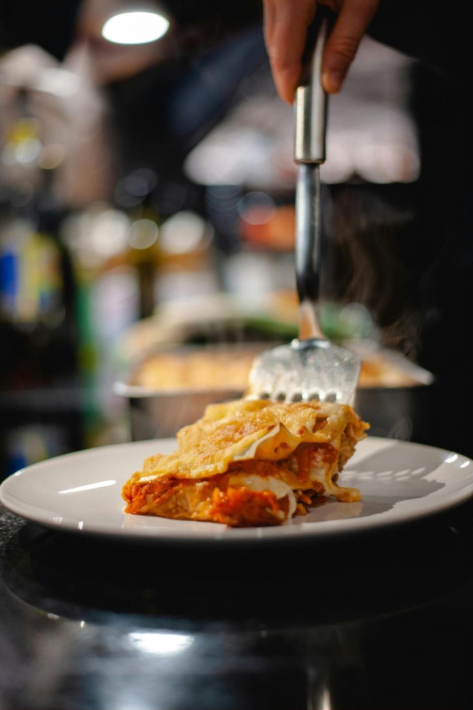 Lasagne al Forno wird auf dem Teller angerichtet