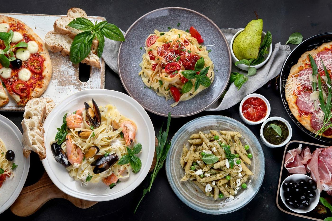 Tavolata: Pizza, Pasta, Antipasti und Salate auf einem langen Tisch